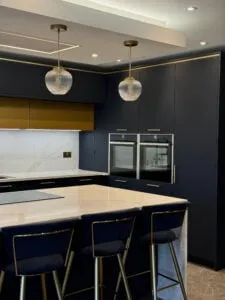 Waterfall kitchen island with quartz worktops and integrated NEFF appliances in a navy blue kitchen